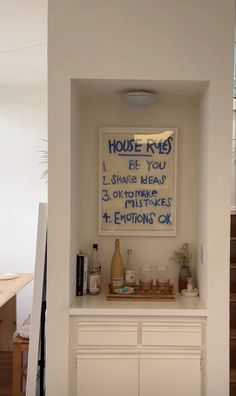 there is a sign that says house rules on the wall in front of a white cabinet