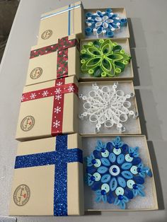 four boxes with different designs on them are sitting on a table together, one is open and the other has snowflakes