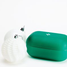two green and white objects sitting next to each other on a white surface with one object in the foreground