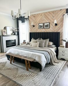 a bedroom with a large bed, fireplace and wooden paneled wall behind the headboard