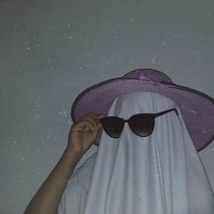 a person wearing a purple hat and sunglasses with a white cloth covering their face to protect them from the sun
