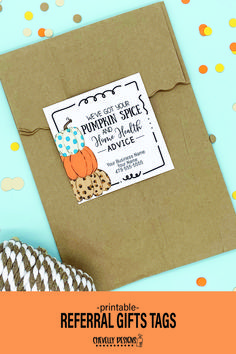a brown envelope with an orange and white tag on it, next to some paper pumpkins
