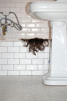 a woman is upside down in the bathtub with her hair flying from under the faucet