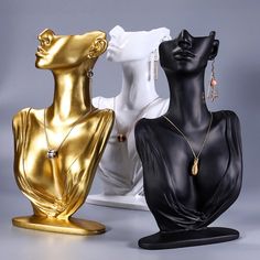 three gold and black mannequins with necklaces on them