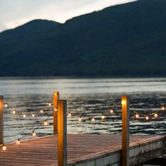 a wooden dock with lights on it and mountains in the background