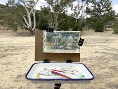 an easel sitting on top of a dirt field
