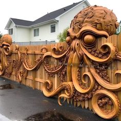 an intricately carved wooden fence in front of a house with a large head on it