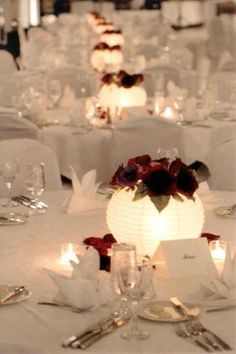 the tables are set with white linens and flowers on them, along with candles
