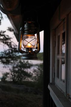 an old fashioned lantern hanging from the side of a building with trees in the background