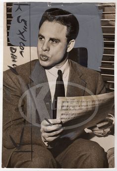 a man in a suit and tie holding a piece of paper with writing on it