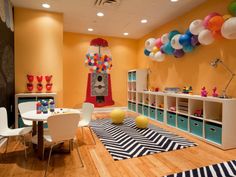 a child's playroom with balloons and toys on the wall, along with white tables and chairs