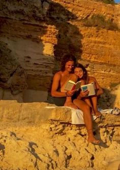 a man and woman sitting on rocks reading books