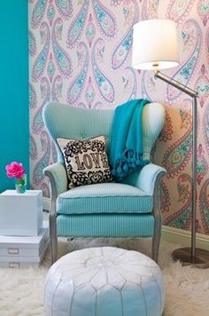 a blue chair and ottoman in front of a wallpapered room with pink flowers