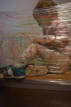 a boy sitting on the floor with his hands wrapped in plastic