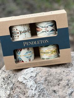 three cups are sitting in a box on top of a rock, with the words pendleton printed on them