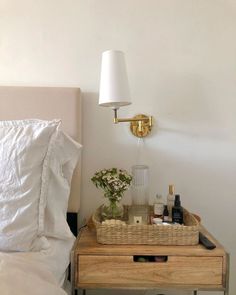 a bedroom with a bed, nightstand and lamp on the night stand next to it