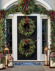 christmas wreaths and lanterns are on the front door
