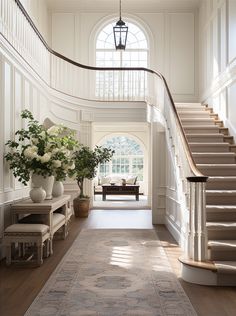 an elegant entryway with stairs and vases filled with flowers on either side of the staircase