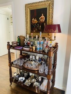 an old fashioned bar cart filled with liquor bottles and glasses on top of a hard wood floor
