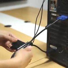 two hands holding wires connected to a computer