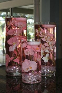three vases filled with pink flowers on top of a table next to each other