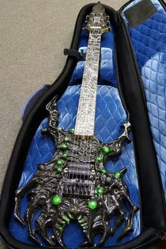 an electric guitar in its case is decorated with green beads and black metal gadgets