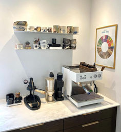 a coffee maker sitting on top of a counter next to cups and other kitchen items
