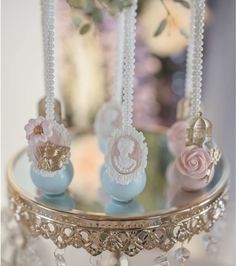 there are three small candy candies on the cake stand with pearls and beads around them