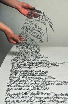 two hands are writing on an old paper with cursive writing and inking
