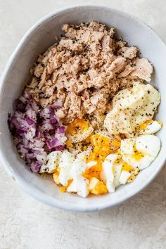 a bowl filled with eggs, meat and other ingredients for an egg salad on a table