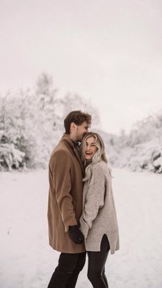 a man and woman are standing in the snow