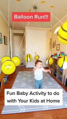 a baby is playing with balloons in the living room while another child watches from the other side