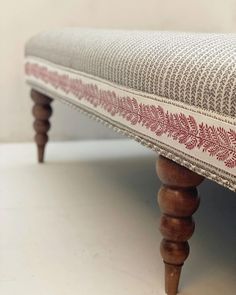 an upholstered bench with red and white fabric on it's backrest