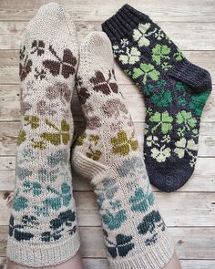 two pairs of knitted socks with flowers and leaves on them sitting next to each other