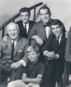 a group of men in suits and ties posing for a photo on the stairs with their arms around each other