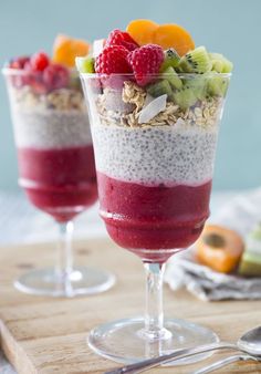 two glasses filled with fruit and granola on top of a table