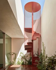 a red spiral staircase in the middle of a building with plants growing on it's sides