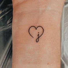 a small heart shaped tattoo on the wrist