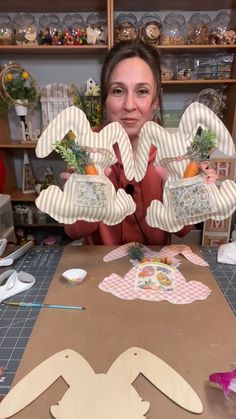 a woman sitting at a table with some paper cut outs in the shape of rabbits