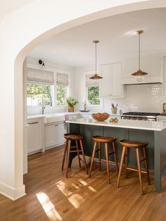 a kitchen with two stools in front of the island and an archway leading into the room