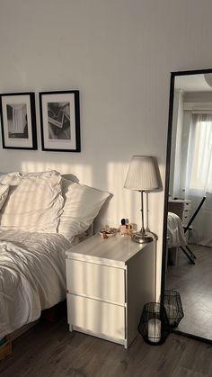 a bedroom with a bed, mirror and lamp on the floor in front of it