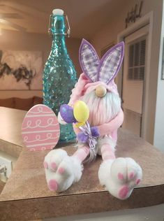 a stuffed animal with bunny ears sitting on a counter next to a bottle and balloon