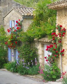 an old stone house with flowers growing on the windowsills and door to another building