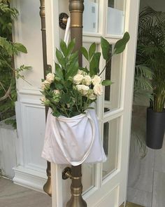 a white flower pot sitting on top of a metal pole next to an open door