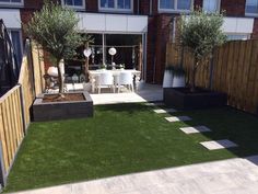 an outdoor patio with artificial grass and potted trees