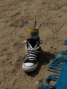 a pair of sneakers with a drink in the middle sitting on top of a beach
