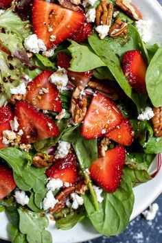 a salad with spinach, strawberries and feta cheese on top is ready to be eaten