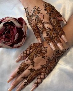 two hands with henna tattoos and a flower