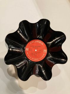 a record in the shape of a flower on a white wall with an orange label