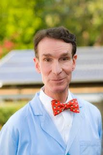 a man in a blue suit and red bow tie posing for a photo with solar panels in the background